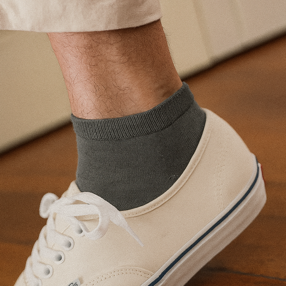 Sustainable khaki ankle socks made from lyocell, worn with white sneakers on wooden floor – Klue lookbook photo.