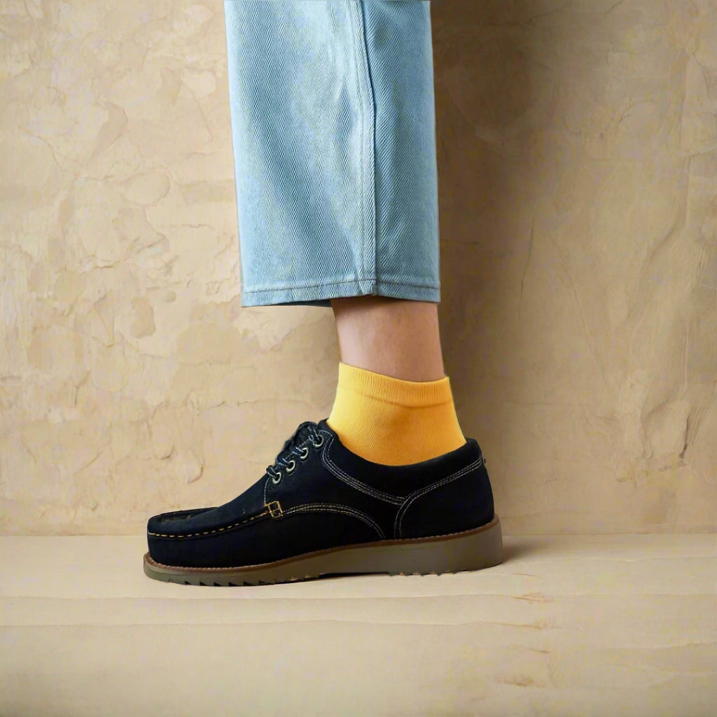 Sustainable yellow ankle socks made from lyocell, worn with white sneakers on wooden floor – Klue lookbook photo.