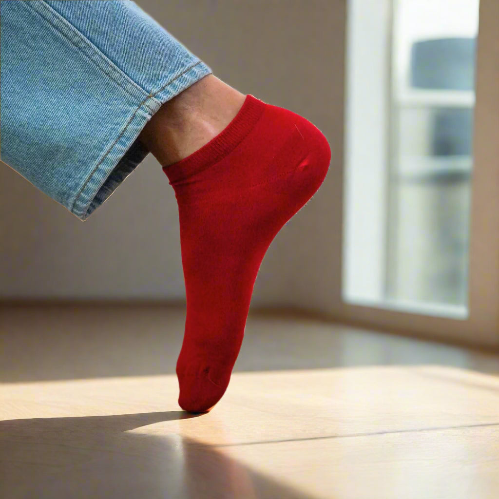 Sustainable red ankle socks made from lyocell, worn with white sneakers on wooden floor – Klue website photo.